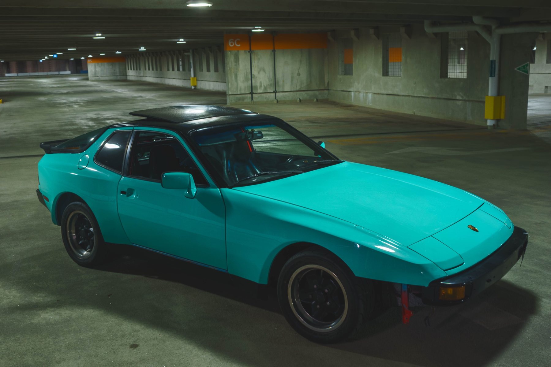 Juan's teal 1984 Porsche 944 with a black roof, parked in an empty garage