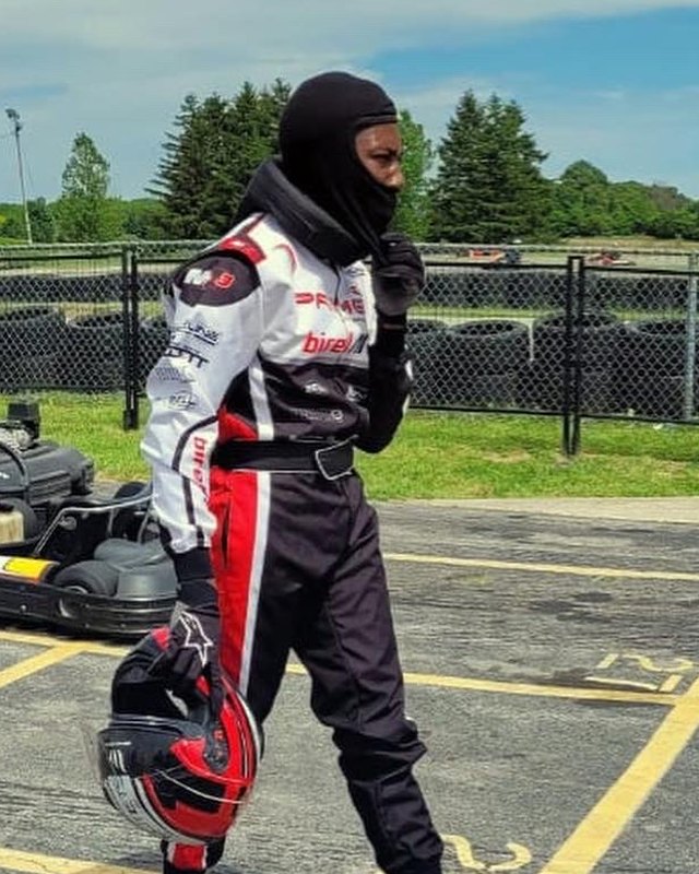 Aaron Montague in his race suit at the kart track, helmet in hand